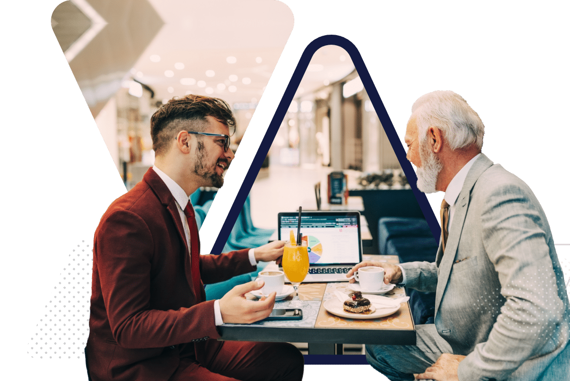 two men sitting in a cafe looking at a laptop