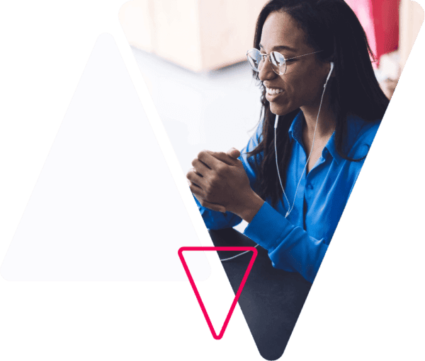 A woman wearing ear phones and sitting at a desk.